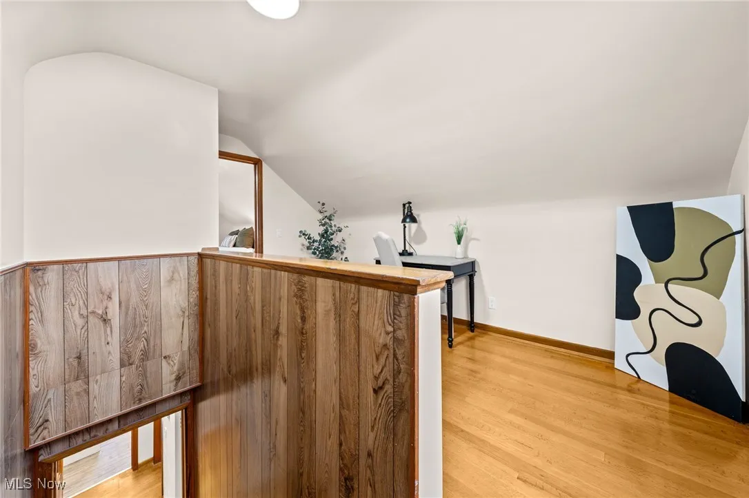 Bar with light wood-style flooring, lofted ceiling, and light countertops