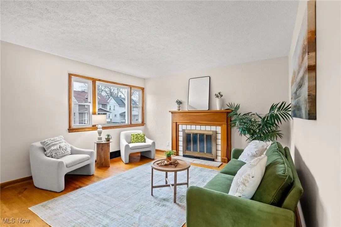 Living room with a fireplace, a textured ceiling, and wood finished floors