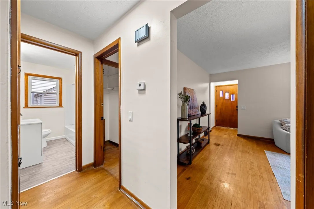 Hallway with light wood-style flooring and a textured ceiling