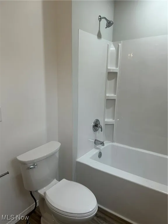 Bathroom with shower / bathtub combination and dark wood-type flooring