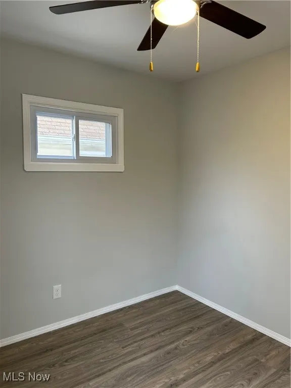 Spare room with a ceiling fan and dark wood finished floors