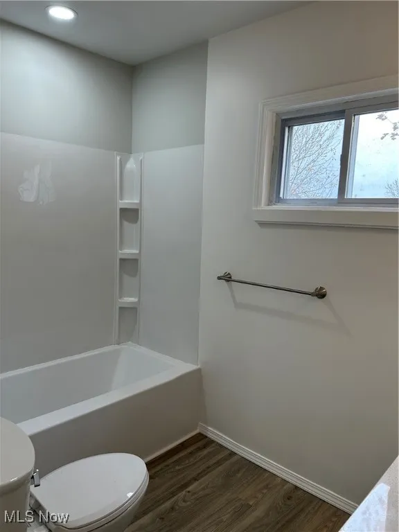 Full bathroom with dark wood-type flooring, bathing tub / shower combination, and recessed lighting