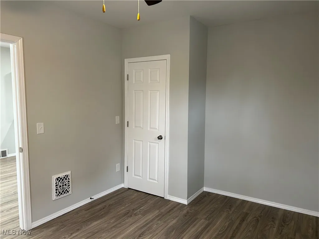 Unfurnished bedroom featuring dark wood-type flooring and baseboards