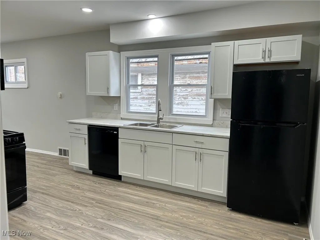 Kitchen featuring black appliances, white cabinetry, light wood finished floors, and recessed lighting