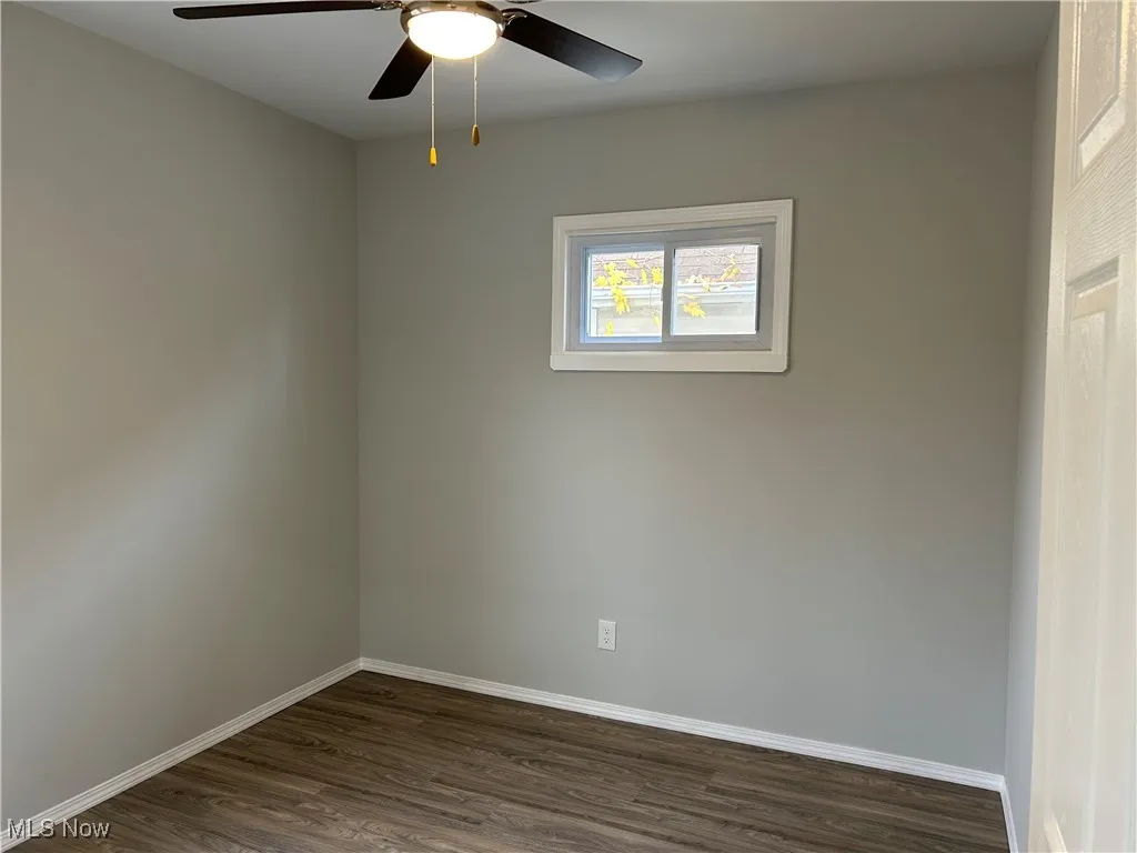 Unfurnished room with dark wood finished floors and ceiling fan