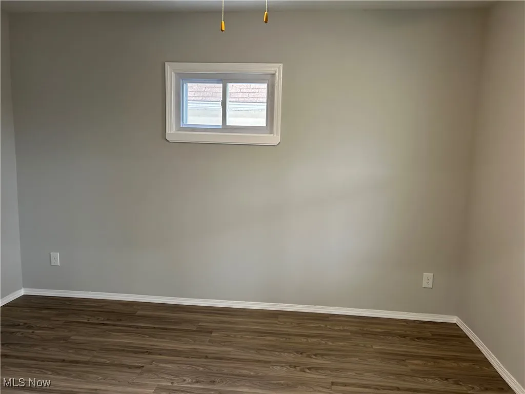 Unfurnished room with dark wood-style floors and baseboards