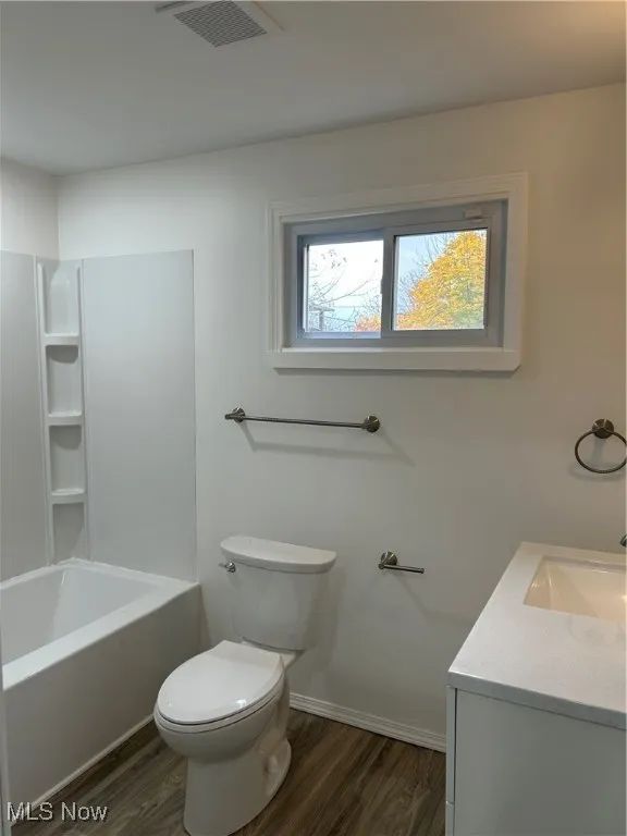 Bathroom with dark wood-style floors, vanity, and washtub / shower combination