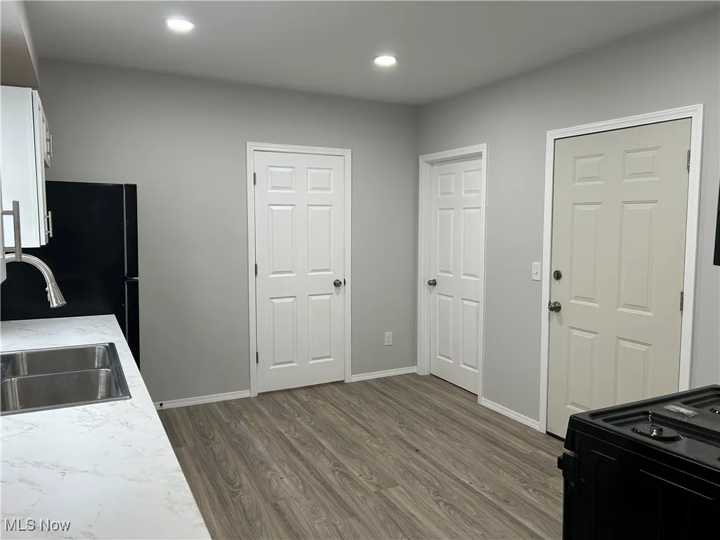 Kitchen featuring dark wood-type flooring, black range with gas stovetop, white cabinets, and recessed lighting