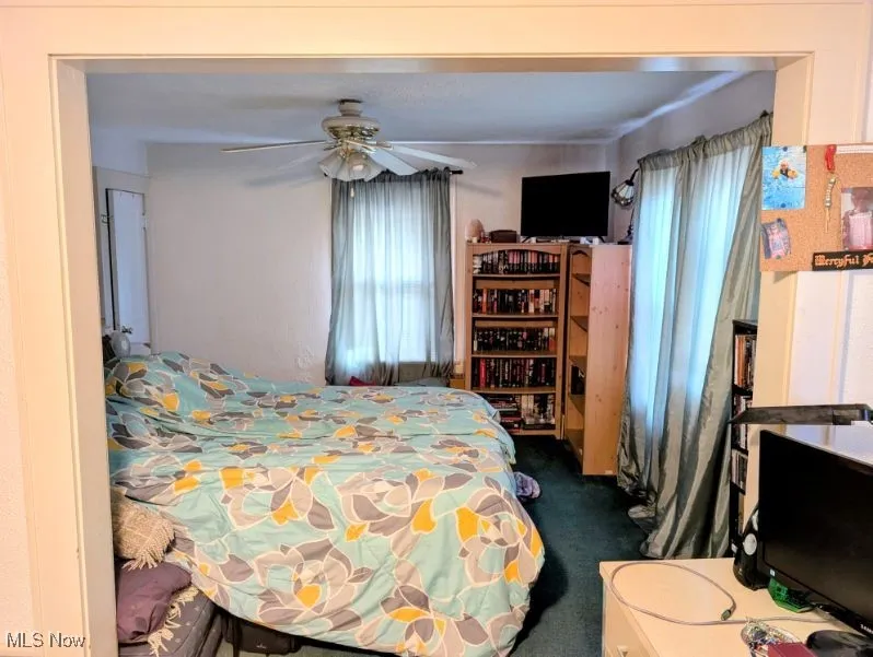 Bedroom with dark colored carpet and ceiling fan