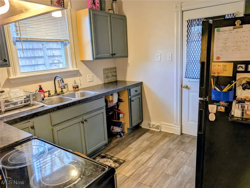 Kitchen with dark countertops, black appliances, wood finish floors, and gray cabinetry