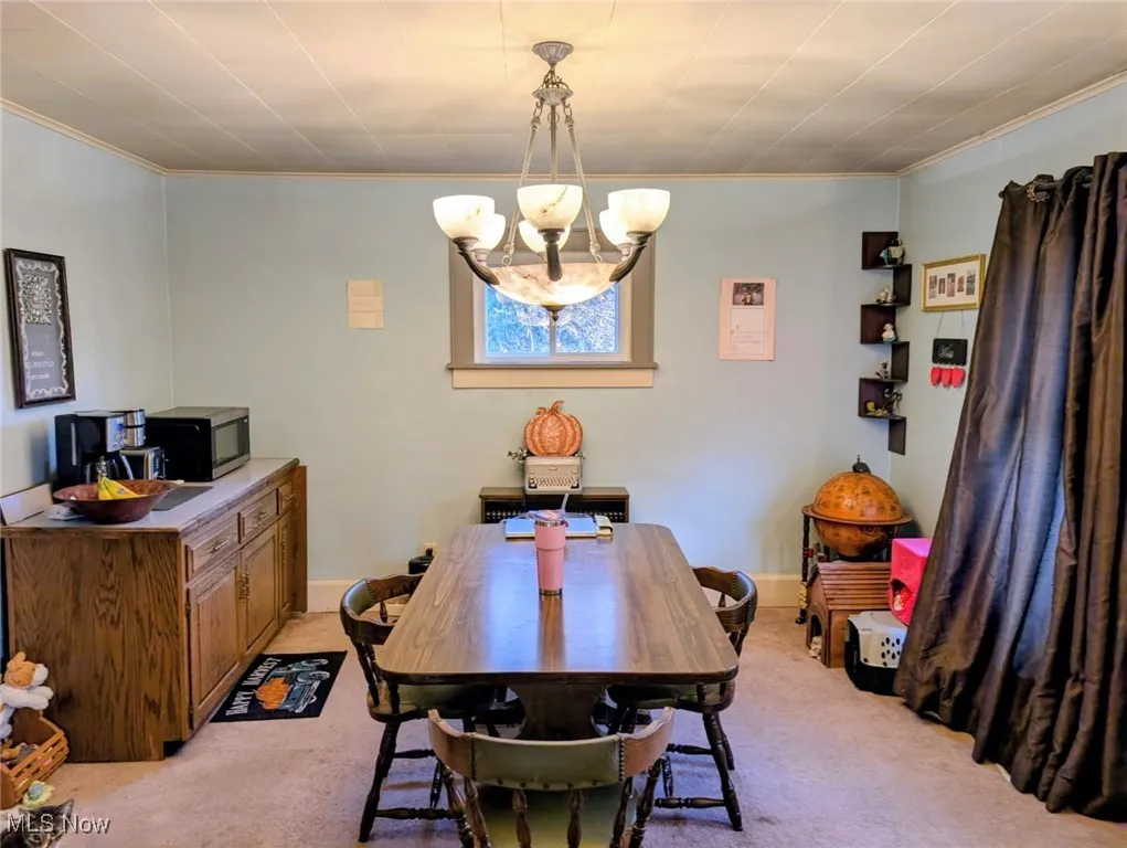 Dining room featuring crown molding, light carpet, and a chandelier