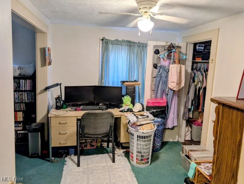 Office area featuring a textured ceiling, ceiling fan, and carpet