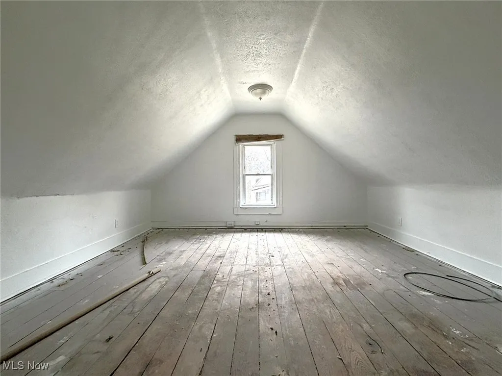 Additional living space featuring a textured ceiling, vaulted ceiling, and wood-type flooring