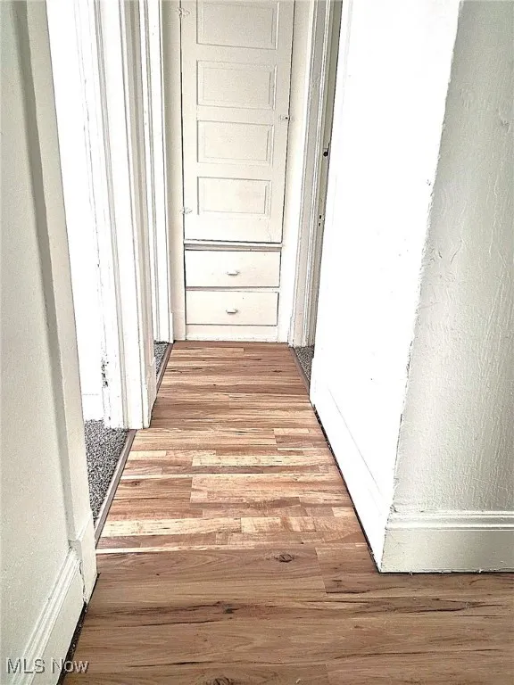 Hall featuring a textured wall and light wood finished floors