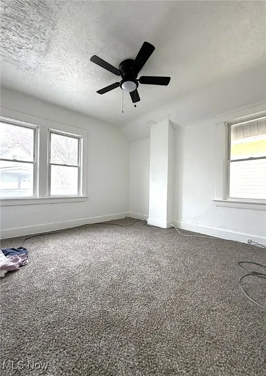 Carpeted empty room with a textured ceiling and plenty of natural light