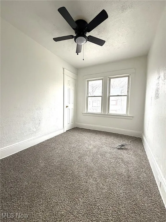 Carpeted spare room with a textured wall, a textured ceiling, and ceiling fan