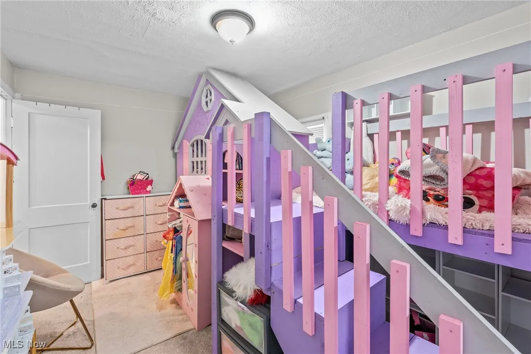 Bedroom with a textured ceiling and light colored carpet