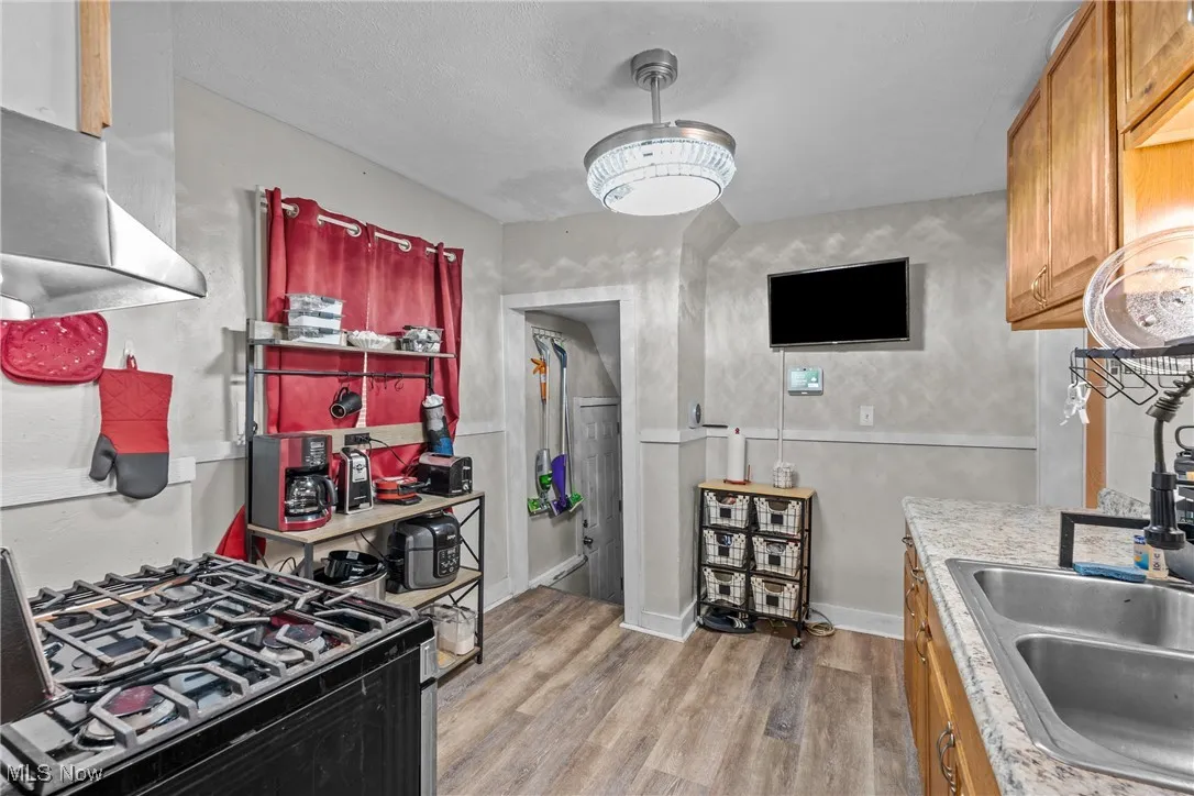 Kitchen featuring light wood-type flooring, black range with gas cooktop, light countertops, and brown cabinetry