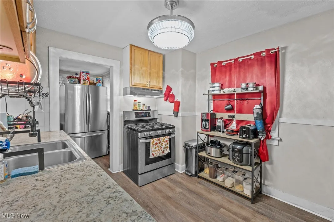 Kitchen featuring stainless steel appliances, light countertops, wood finished floors, and under cabinet range hood