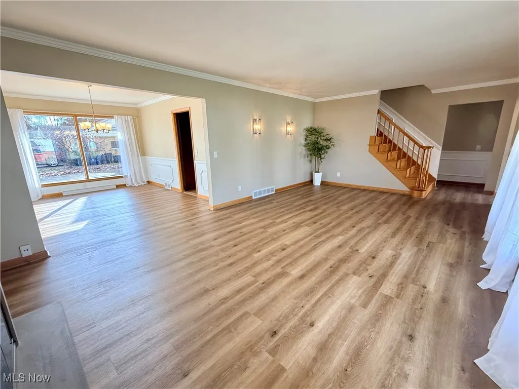Living room and dining room view with newly installed LVP floors a large picture window and beautiful sconces.