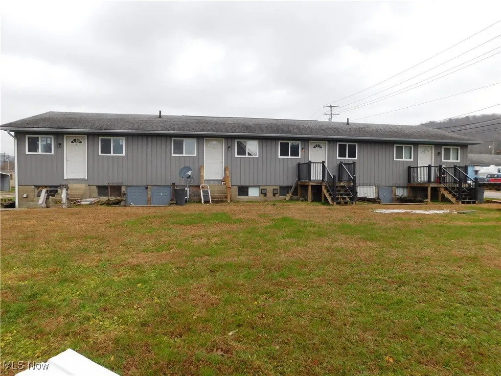 Back of property with a lawn and roof with shingles