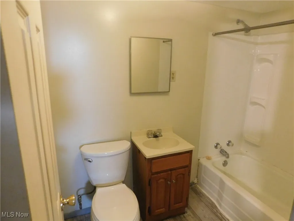 Bathroom with shower / bath combination, vanity, and light wood-style flooring