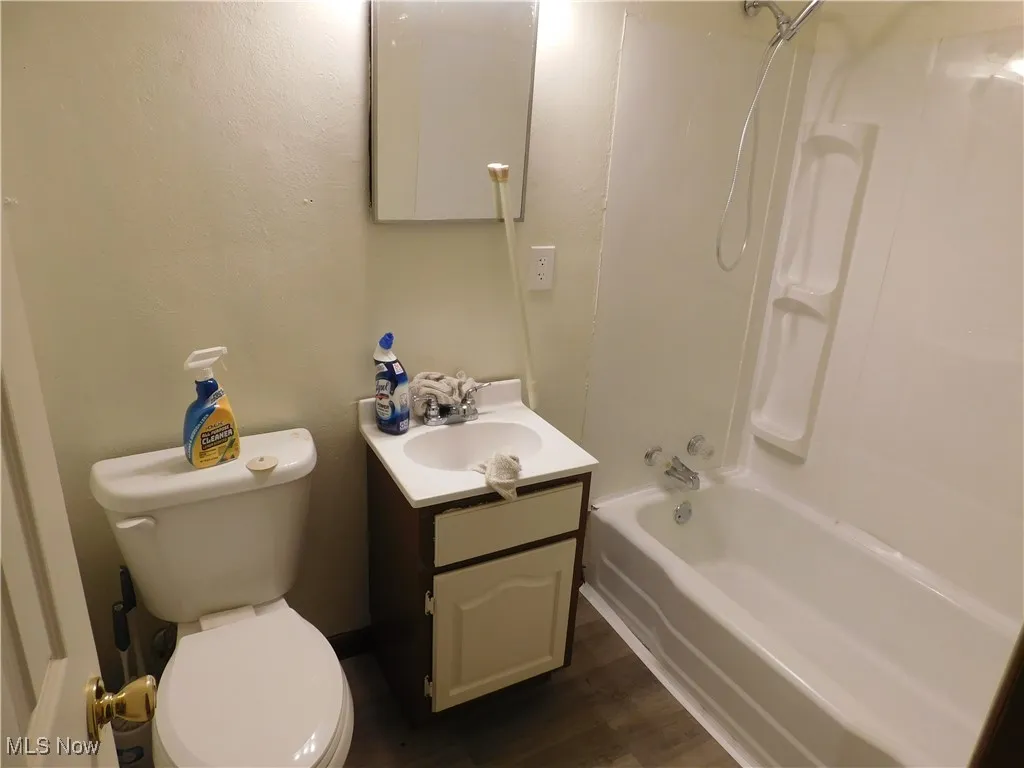 Full bathroom featuring vanity, washtub / shower combination, and dark wood-style floors
