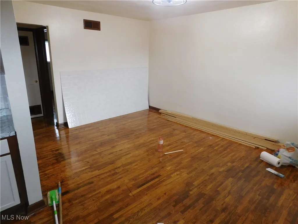 Unfurnished room with dark wood finished floors and baseboard heating