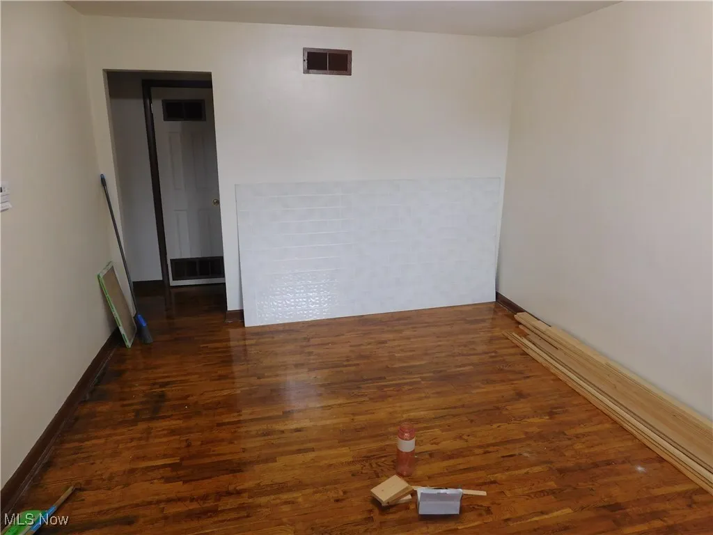 Spare room featuring dark wood-type flooring and baseboards