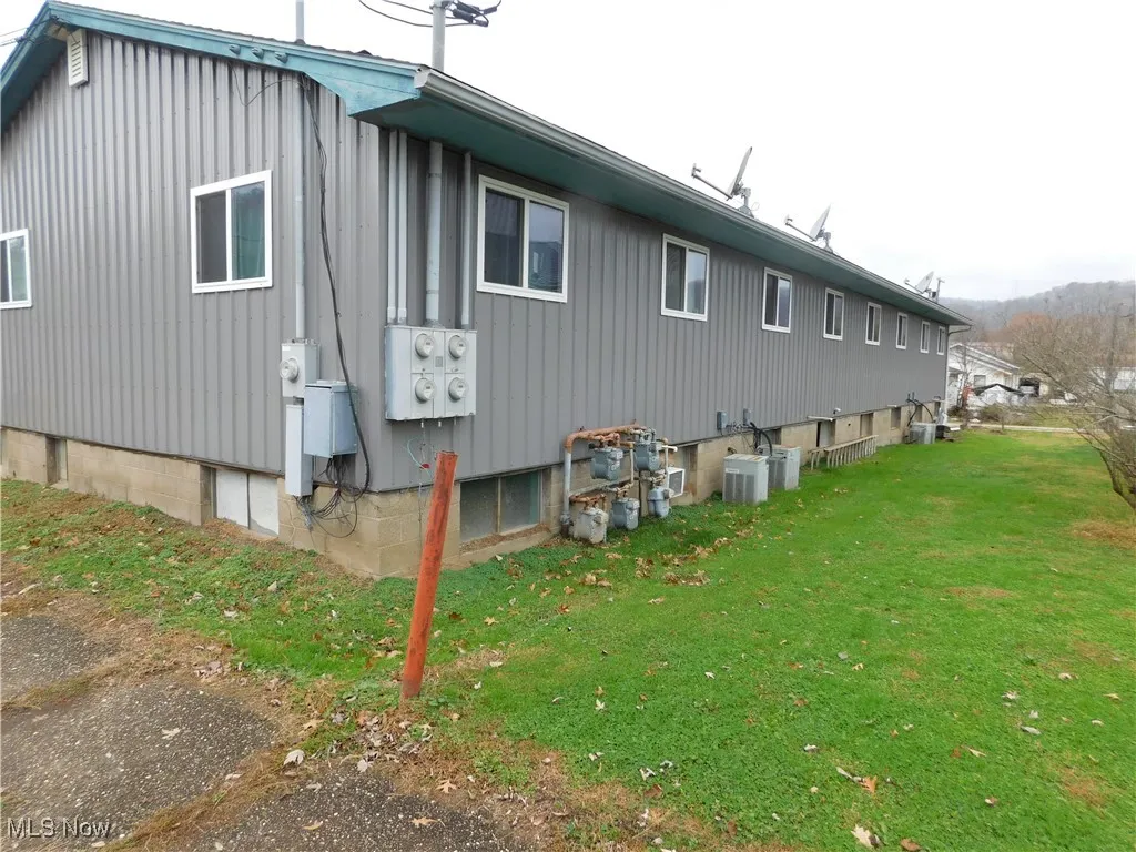 View of property exterior featuring a lawn and a central air condition unit