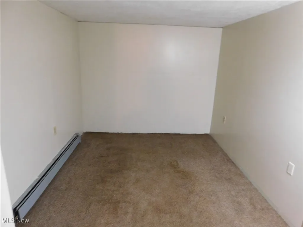 Carpeted empty room with a baseboard radiator