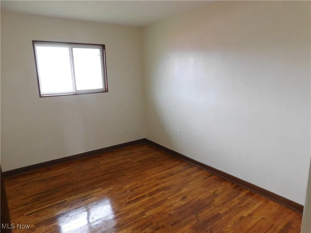 Spare room with dark wood finished floors and baseboards
