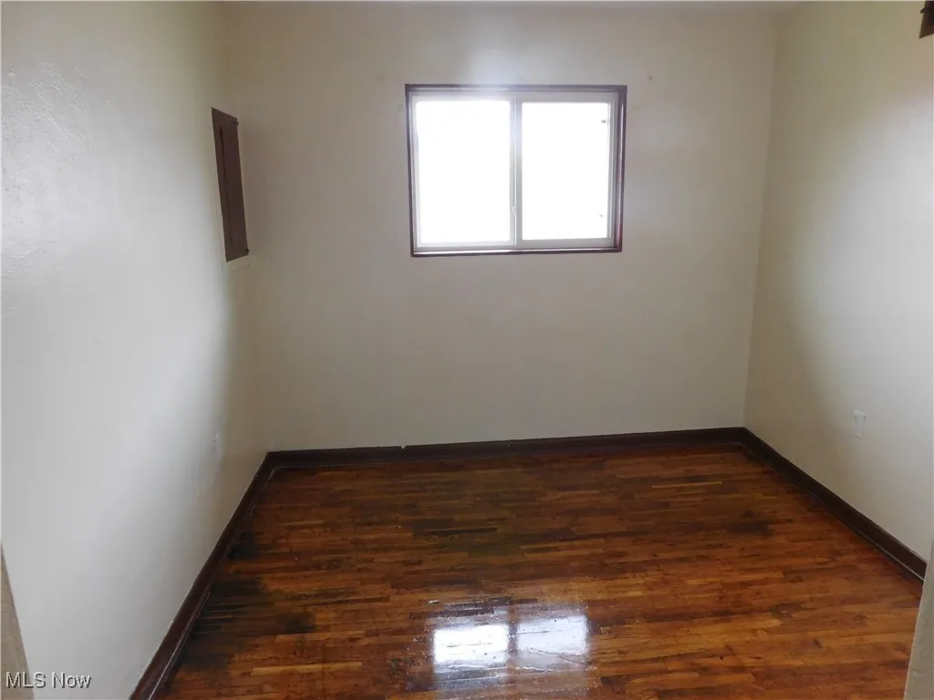 Spare room featuring dark wood finished floors and baseboards