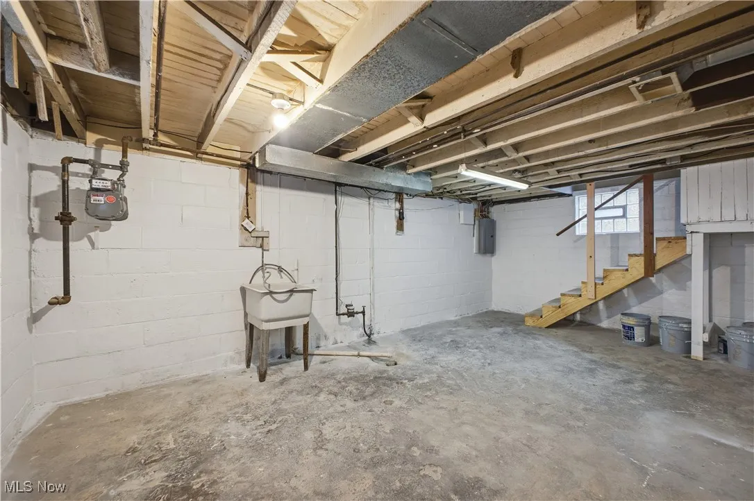 Unfinished below grade area with stairs and electric panel