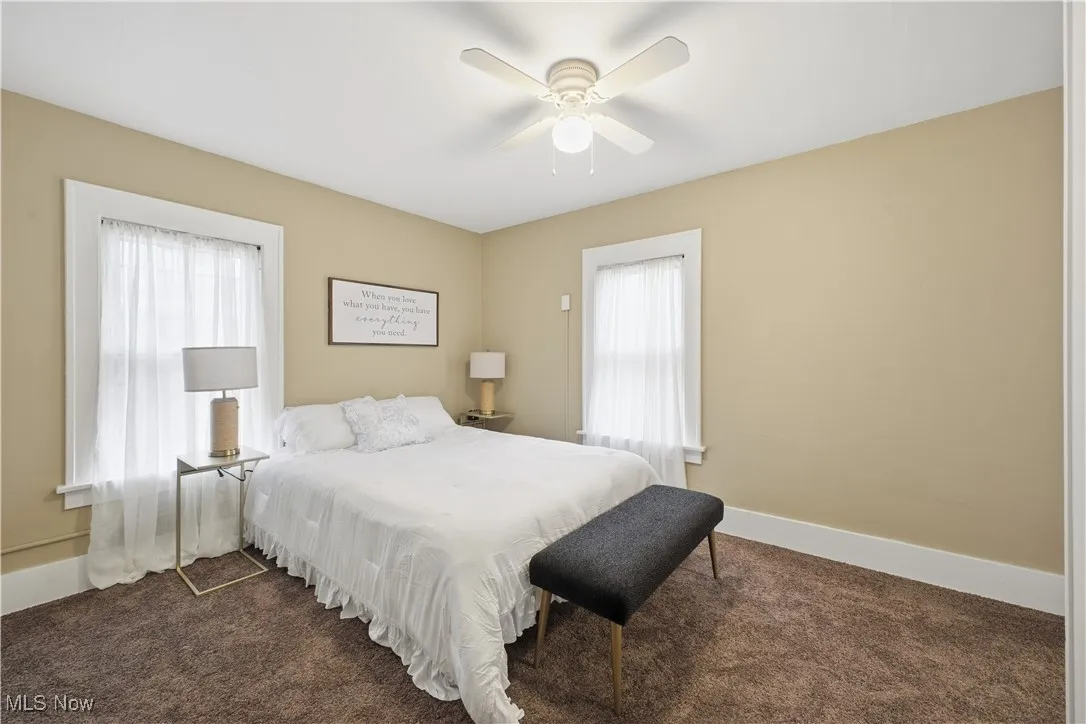 Bedroom with a ceiling fan and dark carpet
