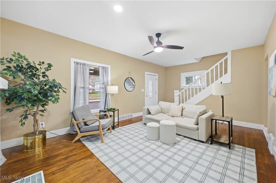 Living room with stairway, hardwood / wood-style floors, and a ceiling fan