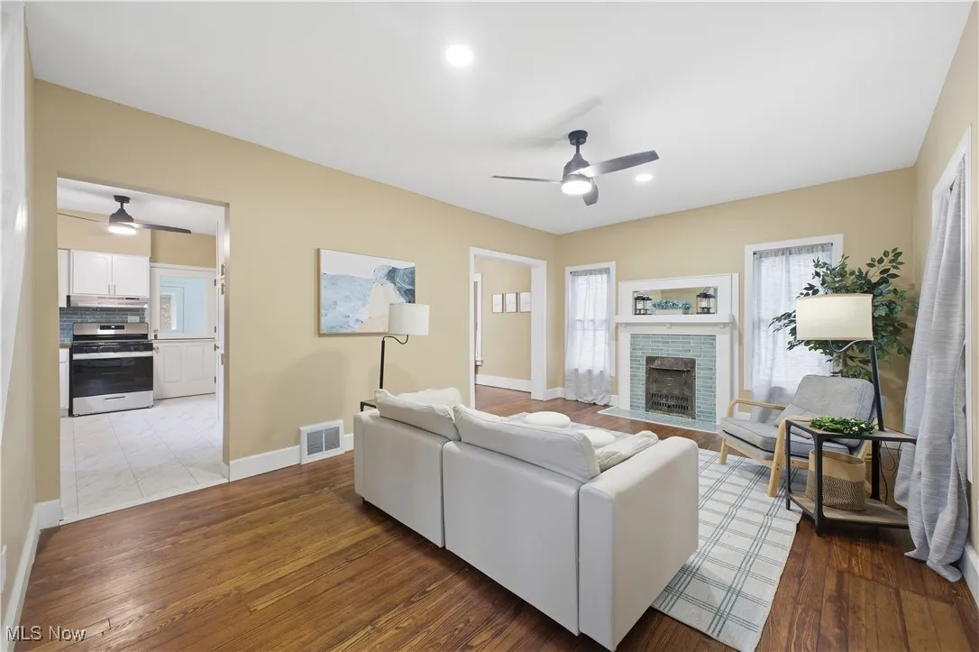 Living room with a ceiling fan, a fireplace, dark wood-type flooring, and recessed lighting