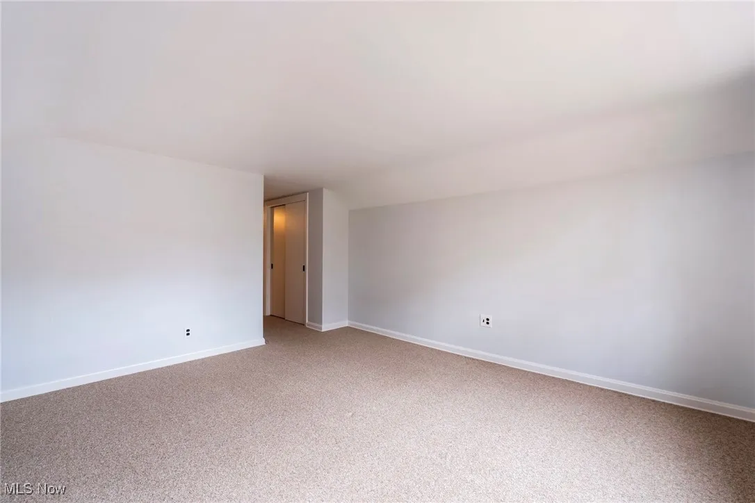 Empty room with baseboards and light colored carpet