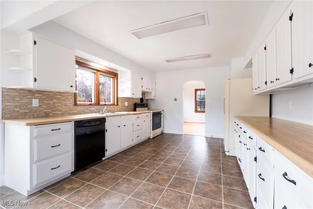 Kitchen with arched walkways, open shelves, range with electric stovetop, and healthy amount of natural light