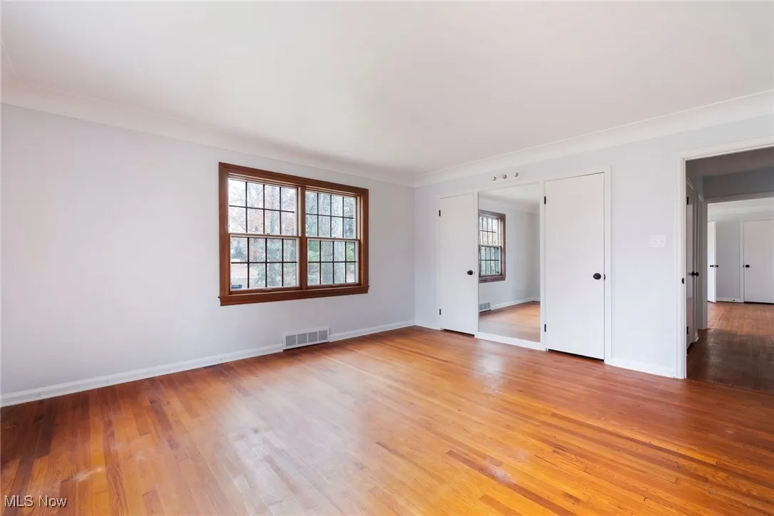 Empty room with light wood-type flooring and crown molding