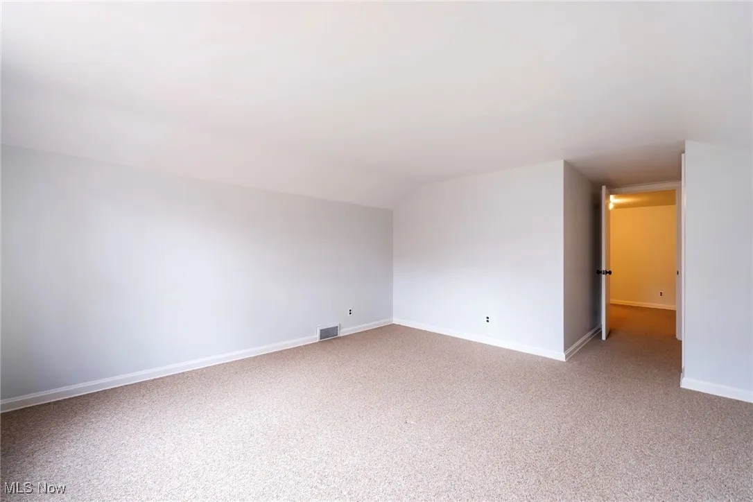 Empty room with light carpet and vaulted ceiling