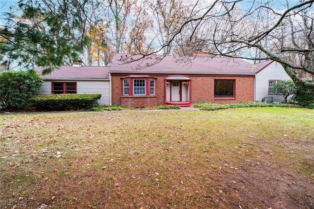 Single story home featuring a chimney, a front lawn, brick siding, and roof with shingles