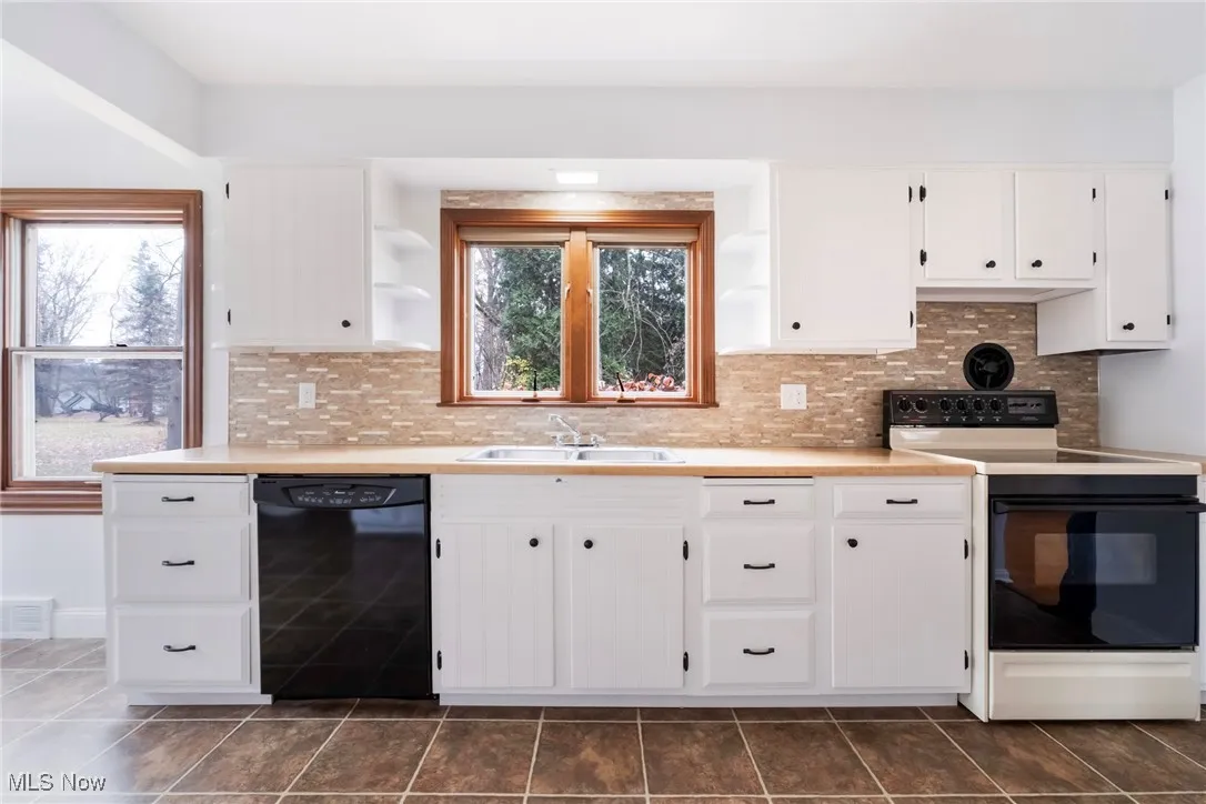 Kitchen featuring open shelves, electric range oven, light countertops, and black dishwasher