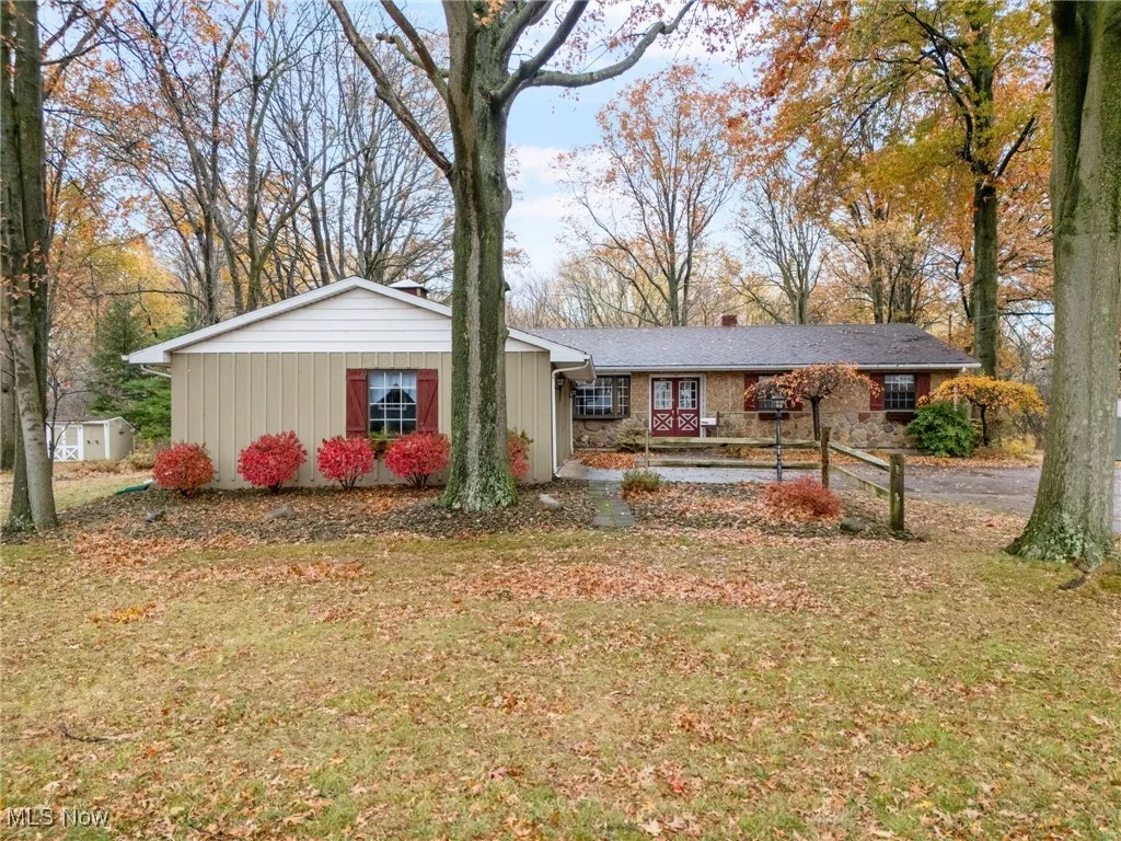 Ranch-style house with a front lawn, board and batten siding, a chimney, and stone siding