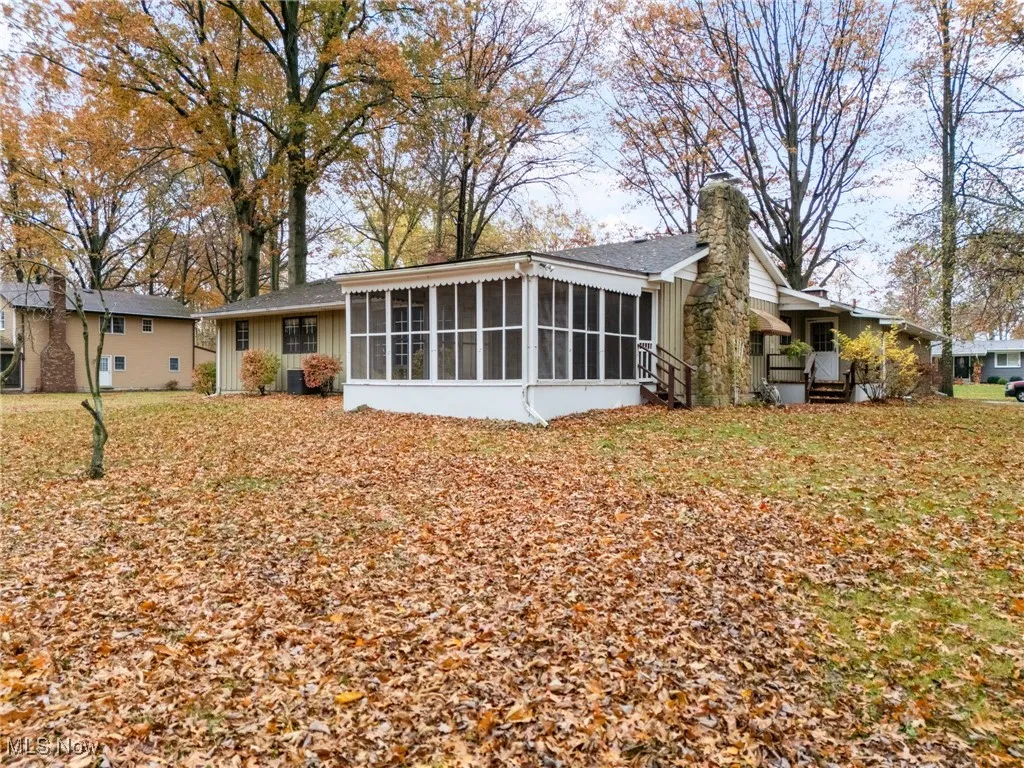 Rear view of property featuring a sunroom  and a large yard