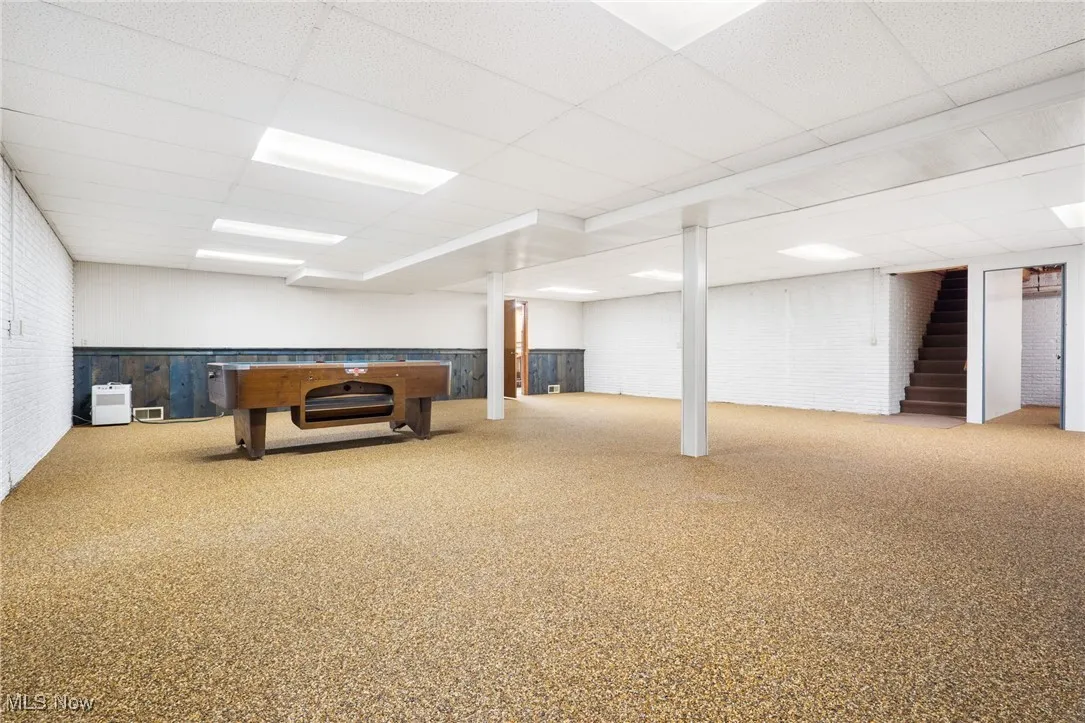 Finished below grade area with naturestone flooring, a drop ceiling, and a brick fireplace