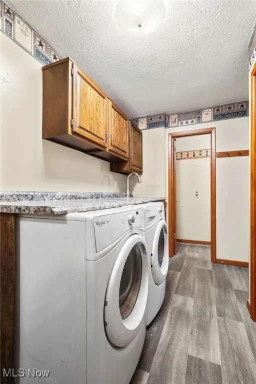 Laundry room with a textured ceiling, cabinet space, and separate washer and dryer