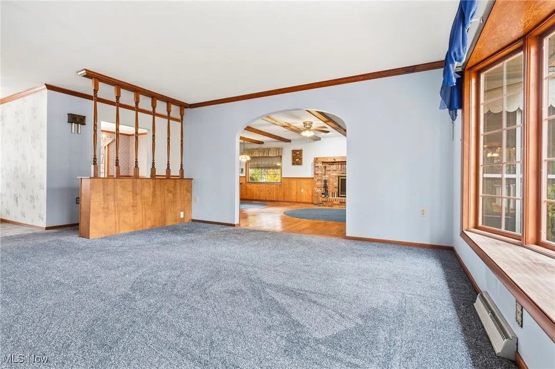 Unfurnished living room with arched walkways and carpet floors