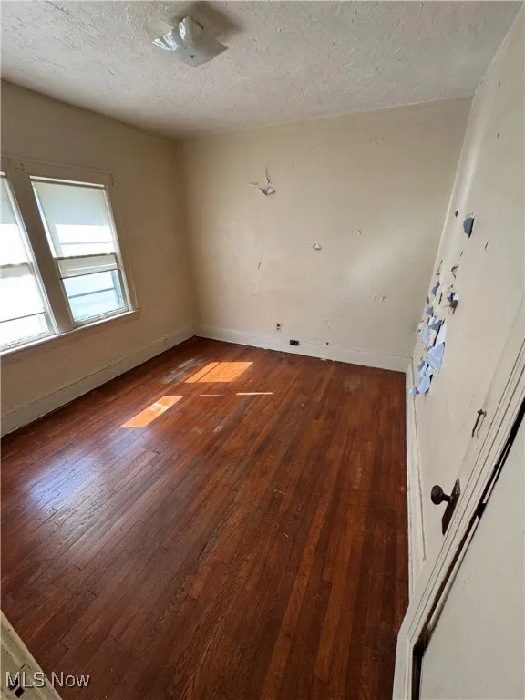 Unfurnished room with hardwood / wood-style flooring and a textured ceiling