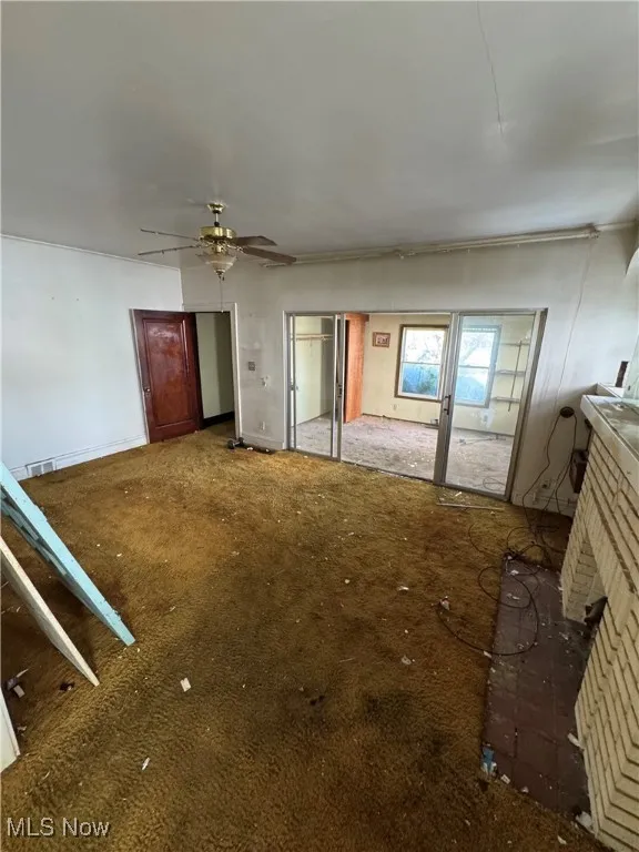 Unfurnished living room featuring carpet flooring and a ceiling fan